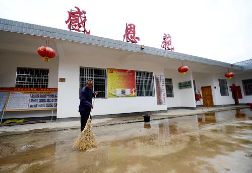在安遠縣三百山鎮(zhèn)烏石村感恩苑,73歲的特困老人謝家輝在清掃地面積水(5月9日攝)。新華社記者 周科攝