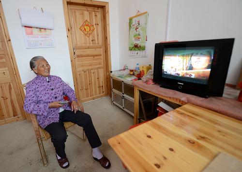 在安遠縣三百山鎮(zhèn)烏石村感恩苑,71歲的特困老人唐壽娣在新房看電視(5月9日攝)。新華社記者 周科攝