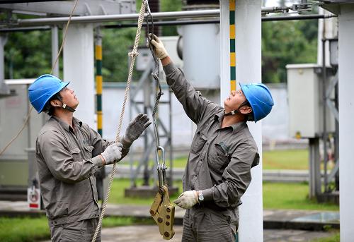 5月16日,兩名電力工人在九江市廬山區(qū)220千伏妙智變電站妙賽1線作業(yè),確保暴雨中的電網(wǎng)正常運轉(zhuǎn)。新華社記者 周科 攝