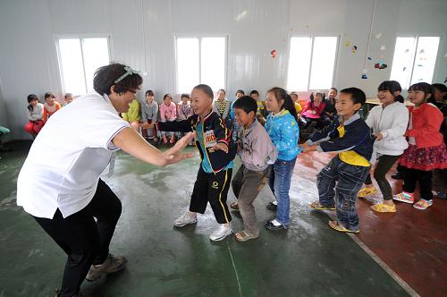 5月14日,在雅安市蘆山縣龍門晨陽希望板房學(xué)校內(nèi)的中國科學(xué)院心理援助工作站心理咨詢輔導(dǎo)室內(nèi),一名心理援助志愿者老師帶領(lǐng)災(zāi)區(qū)小學(xué)生做“老鷹捉小雞”的團體游戲。新華社記者 李曉果 攝