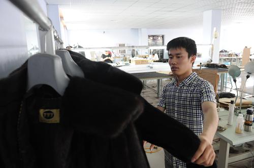 5月19日,在河北省故城縣一家裘皮服裝廠,總經(jīng)理王明磊在檢查裘皮服裝質(zhì)量。故城籍的王明磊2011年從河北科技大學(xué)畢業(yè)后,選擇回鄉(xiāng)跟隨父親創(chuàng)業(yè)。新華社記者 王民 攝
