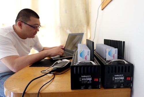 偵查員在犯罪嫌疑人住地查看作案使用的短信群發(fā)器。新華社記者 凡軍 攝