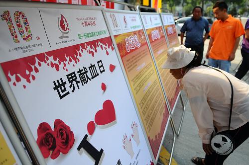 6月14日,在山東省聊城市金鼎廣場,市民在觀看無償獻(xiàn)血光榮榜。