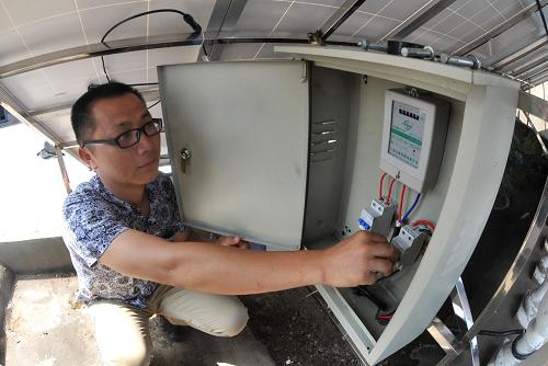 劉銳在樓頂檢查太陽(yáng)能電池板的控制裝置(6月14日攝)。新華社記者 龍弘濤 攝