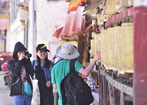 6月15日,游客在拉薩八廓街上拍照留念。據(jù)西藏旅游局?jǐn)?shù)據(jù)顯示,2013年1至5月份,拉薩市累計(jì)接待國內(nèi)外游客超百萬人次,比去年同期增長35.86%;實(shí)現(xiàn)旅游收入10.33億元,比去年同期增長49.35%。 新華社發(fā)(劉坤 攝)