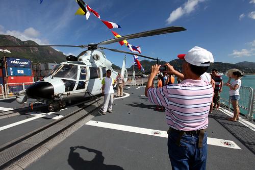 6月16日,在塞舌爾維多利亞港,民眾在哈爾濱艦上和艦載直升機合影留念。新華社記者 饒饒 攝