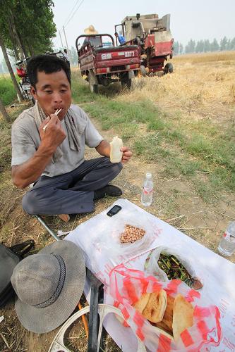 6月16日,在山東臨沂市郯城縣郯城街道官路東村,“麥客”魏延增在麥收間隙吃午飯。新華社發(fā)(張春雷 攝)