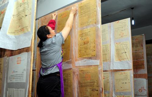 6月23日,四川省鄰水縣檔案館的工作人員將修裱后的國(guó)家重點(diǎn)檔案晾干。新華社發(fā)(邱海鷹 攝)