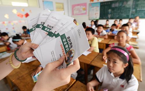 6月24日,國(guó)家電網(wǎng)山東省鄒平縣供電公司工作人員為鄒平縣范公小學(xué)學(xué)生分發(fā)安全用電讀本。新華社發(fā)(董乃德 攝)