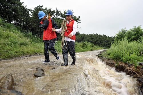 7月12日,國家電網(wǎng)山東煙臺棲霞供電公司搶修人員走在35千伏觀里一線的搶修路上。新華社發(fā)(任夢雪 攝)