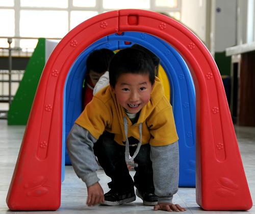 7月17日,玉樹縣第二幼兒園的小朋友在做鉆彩虹橋的游戲。新華社記者 王建華 攝