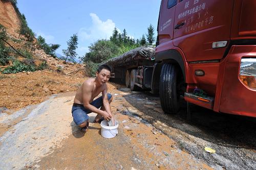 8月21日,一位被困司機(jī)在廣西武(宣)平(南)公路上洗毛巾,準(zhǔn)備擦洗身子。新華社記者 周華 攝