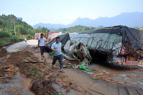 8月21日,兩位被困司機(jī)從廣西武(宣)平(南)公路上一處交通事故現(xiàn)場(chǎng)走過(guò)。新華社記者 周華 攝