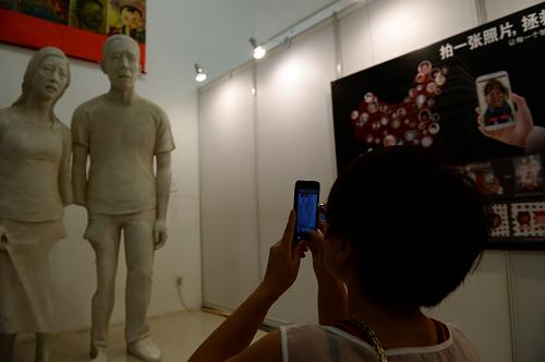 這是展覽上展出的一款手機(jī)APP“失蹤的孩子”,人們可通過(guò)拍攝以一家三口合影為原型的雕像,在手機(jī)中展現(xiàn)雕像鏤空部分(丟失兒童)的真實(shí)故事(8月24日攝)。新華社記者 金良快 攝