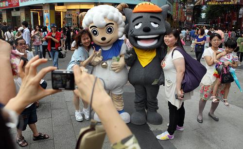 2010年6月19日,游客在臺北西門町與大陸動畫片主角“喜羊羊”、“灰太狼”的大型人偶一起合影。動畫片《喜羊羊與灰太狼》被電視臺引進(jìn)臺灣后,贏得臺灣小朋友的喜愛。新華社記者 費茂華 攝