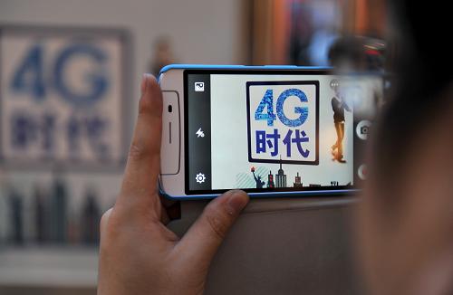 12月19日,在唐山移動(dòng)4G首場體驗(yàn)會(huì)現(xiàn)場,一名體驗(yàn)者在用4G手機(jī)拍攝推介展牌上的“4G時(shí)代”圖標(biāo)。新華社發(fā)(鄭勇 攝)