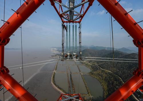 12月19日,浙江省送變電工程公司的施工人員在190多米高的電纜線上安裝附件。當(dāng)日,浙江六橫電廠——春曉500千伏跨海輸電工程全線架通,工程建設(shè)進(jìn)入投運(yùn)前最后沖刺階段。該工程起自浙江舟山六橫電廠,終至浙江寧波500千伏春曉變電站,路徑總長為36.5千米(其中跨海部分為8.39千米),共新建鐵塔74基、平均塔高195米,采用同塔雙回路架設(shè),是目前國內(nèi)最長的500千伏跨海輸電工程。該工程是浙江舟山六橫電廠輸出電能的配套輸電工程,也是浙江舟山聯(lián)網(wǎng)至大陸的首條500千伏線路,總投資約11億元,計劃于2014年1月投運(yùn)。新華社記者 徐昱 攝