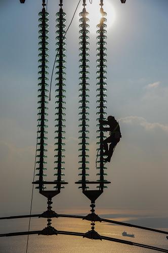 12月19日,浙江省送變電工程公司的施工人員在巡查安裝好的電纜瓷瓶。新華社記者 徐昱 攝