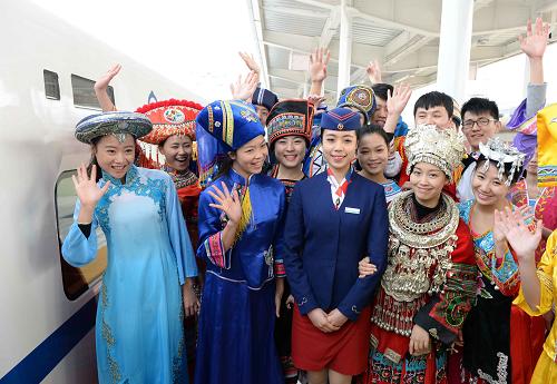 12月30日,在南寧火車站,身著民族盛裝的乘客在搭乘動車前和乘務員合影。新華社記者 周華 攝