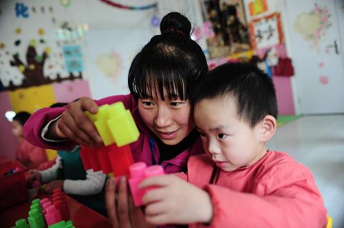 2013年12月31日,西寧市馨樂藝術幼兒園老師柴春燕陪孩子玩游戲。2013年下半年,青海省安排專項資金1億元,實施學前教育推進工程,進一步改善全省范圍內幼兒園基礎設施建設,提升學前教育的質量和水平。新華社發(fā)(李少鵬攝)