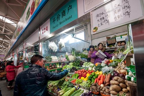 2013年12月31日,顧客在北京市朝陽(yáng)區(qū)三源里菜市場(chǎng)的平價(jià)商戶攤位前挑選蔬菜。2013年改造后,該市場(chǎng)設(shè)立了平價(jià)商戶,減免商戶一部本分費(fèi)用,商戶每天需提供5種以上的平價(jià)“大路菜”。新華社記者 張宇 攝