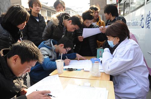 2014年1月1日,人們在蘇州市觀前街的一輛獻(xiàn)血車前填寫“無償獻(xiàn)血表”。 新華社發(fā)(王建中 攝)