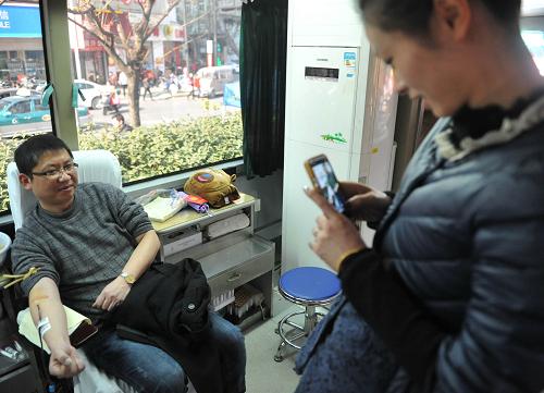 2014年1月1日,在浙江省臨安市街頭的流動(dòng)獻(xiàn)血車內(nèi),一名女士給獻(xiàn)血的男友拍照留念。 新華社發(fā)(胡劍歡 攝)