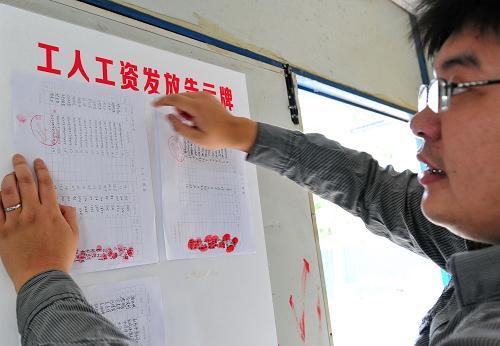1月3日,福建省永泰建筑工程有限公司“東泰華府”建筑工地?zé)o欠薪項(xiàng)目部辦公室工作人員在張貼農(nóng)民工工資發(fā)放表。新華社記者 林善傳 攝