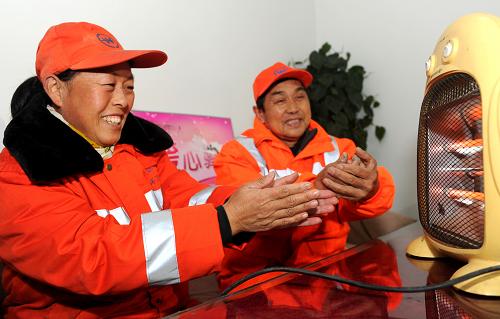 1月8日,兩名環(huán)衛(wèi)工在一處“暖心驛站”內(nèi)取暖。新華社記者 劉軍喜 攝