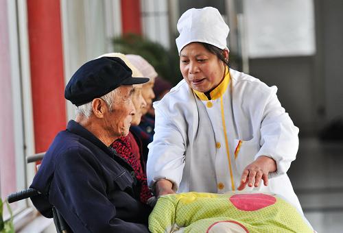 1月9日,山東鄒平縣昶勝老年公寓工作人員給一位坐輪椅的老人蓋棉被。新華社發(fā)(董乃德 攝)