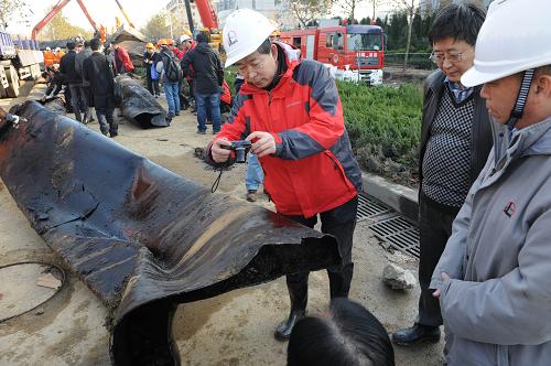這是2013年11月26日拍攝的相關(guān)人員在對清理出的輸油管道進(jìn)行拍攝查看。新華社記者 李紫恒 攝