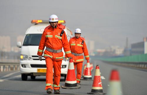 1月26日,甘肅天水高速清障救援一大隊隊員楊世軍(前)正在救援現(xiàn)場設(shè)置安全錐。新華社記者 陳斌 攝