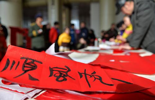 1月27日,在蘭州火車站候車廳,書法愛好者們?yōu)槁每蜁鴮懶麓簩?duì)聯(lián)。新華社記者 陳斌 攝