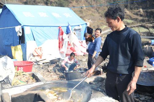 1月30日,在貴州鎮(zhèn)遠縣報京鄉(xiāng)報京村,受災(zāi)村民領(lǐng)到年貨后在救災(zāi)帳篷旁做年夜飯。新華社記者 王念 攝