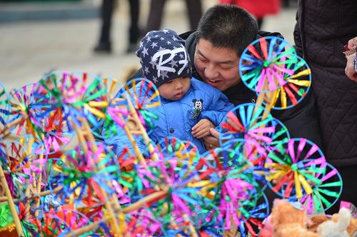 1月31日,在第十九屆北京大觀園紅樓廟會(huì)上,一名家長(zhǎng)給孩子選購(gòu)風(fēng)車(chē)。新華社記者 李鑫 攝