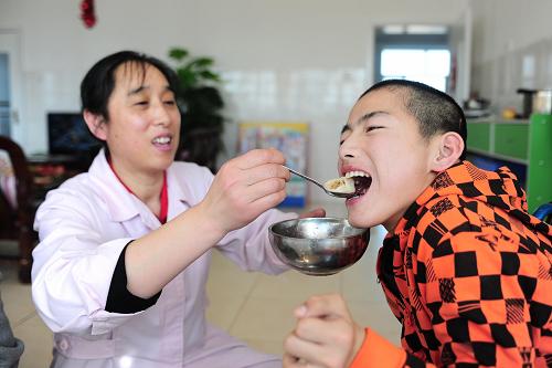 1月31日,西寧市兒童福利院工作人員李玉香(左)在給福利院的孩子袁均喂餃子。新華社發(fā)(李少鵬 攝)