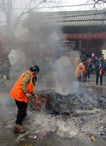 1月31日,廟會工作人員在鄭州城隍廟門前清理路面上堆積的香灰。新華社記者 王頌 攝