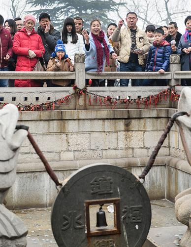 2月1日,游客們?cè)谝豁?xiàng)傳統(tǒng)游藝項(xiàng)目中用硬幣砸向“金錢孔”。新華社記者 李賀 攝