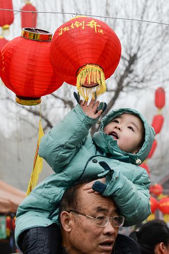 2月1日,在廟會(huì)上,一名小朋友騎在家長(zhǎng)脖子上玩耍。新華社記者 李賀 攝