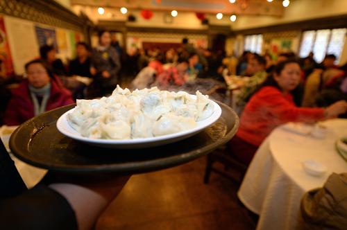 2月4日,在惠豐老北京餃子樓,一名服務(wù)員將一盤餃子端送給顧客。新華社記者 李鑫 攝