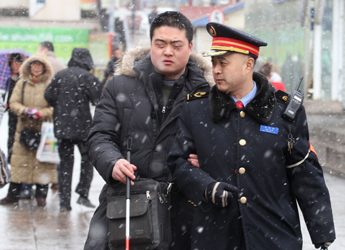 2月5日,鐵路青島客運(yùn)段工作人員劉波(右)在風(fēng)雪中護(hù)送剛抵達(dá)的盲人旅客搭乘出租車。據(jù)中央氣象臺監(jiān)測數(shù)據(jù)顯示,自5日5時至6日5時,我國中東部一帶的降水范圍明顯擴(kuò)大,馬年首輪大范圍雨雪天氣逐步展開。此輪中東部地區(qū)的大范圍雨雪天氣過程恰逢春運(yùn)返程客流高峰期,雨雪天氣和道路結(jié)冰對春運(yùn)返程交通運(yùn)輸造成較大影響。新華社發(fā)(王海濱 攝)
