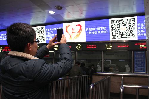 2月11日,在西安火車站售票大廳,一名旅客用手機(jī)微信掃描“西安車站微助手”二維碼。新華社發(fā)(唐振江 攝)
