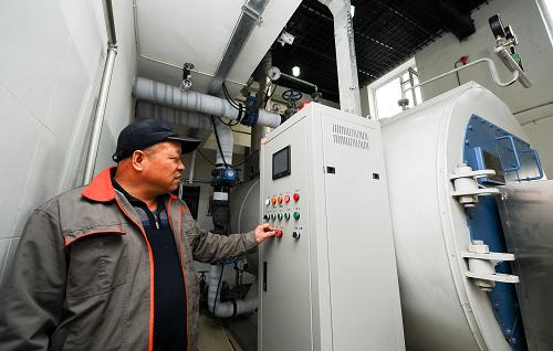 2月26日,司爐工張長延在通過自動化設(shè)備控制鍋爐內(nèi)燃燒情況。2013年冬,吉林省長春市啟動“煤改氣”供熱試點建設(shè),首批進(jìn)行改造的3個鍋爐房涉及供熱用戶上千戶,并計劃利用三年時間,逐步將長春市三環(huán)內(nèi)277座供熱小鍋爐進(jìn)行“煤改氣”改造。2月26日,記者在長春市一處“煤改氣”試點看到,冒著濃濃黑煙的“大煙囪”已不復(fù)存在,取而代之的則是一個“小煙囪”在不時地冒著白色的水蒸氣。將近一個供熱周期過后,鍋爐房內(nèi)依舊是窗明幾凈,沒有了煙灰和煤渣。“以前燃煤時總是煙塵飛揚,現(xiàn)在改成燃?xì)夂笈欧盼锘緸槎趸己退?,對空氣的污染要小得多?#8221;司爐工張長延說,“你就單看我,以前身上總是黑乎乎的,下班后第一件事就是洗澡。如今我這身工作服已經(jīng)一個月沒洗了,你能看出來嗎?”新華社記者 許暢 攝