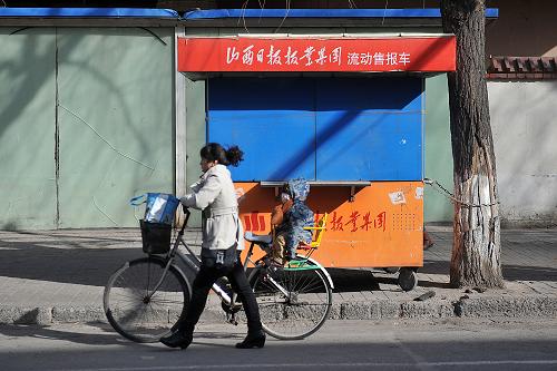 2月27日,在太原市羊市街,一位市民推著車(chē)從一家停業(yè)的流動(dòng)售報(bào)車(chē)旁走過(guò)。新華社記者 詹彥 攝