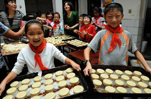 9月7日,六安市裕安區(qū)固鎮(zhèn)鎮(zhèn)中心小學的兩名留守兒童在展示學生們制作的月餅。新華社發(fā)(陳力 攝)