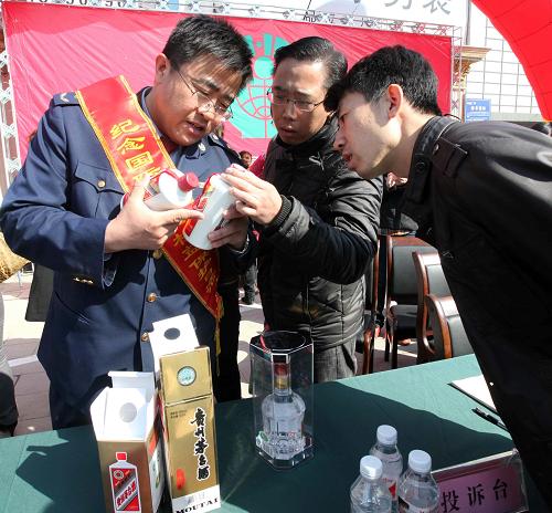 3月14日,山東省濰坊市高新區(qū)工商執(zhí)法人員在向消費(fèi)者講解如何辨別假冒偽劣酒產(chǎn)品。新華社發(fā)(張馳 攝)