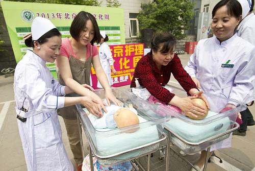 5月6日,在北京宣武醫(yī)院,幾名觀眾在護(hù)理人員的指導(dǎo)下體驗(yàn)嬰兒護(hù)理。當(dāng)日,2013年北京護(hù)理文化周開幕式在北京宣武醫(yī)院舉行。宣武醫(yī)院的護(hù)理人員在現(xiàn)場(chǎng)開展了融急救、科普、實(shí)操為一體的護(hù)理公益活動(dòng)。護(hù)理工作者通過模擬教具、互動(dòng)體驗(yàn)、咨詢解答等形式,從降低發(fā)病率、挽救生命、改善預(yù)后三方面普及護(hù)理知識(shí)。新華社發(fā)(趙冰 攝)