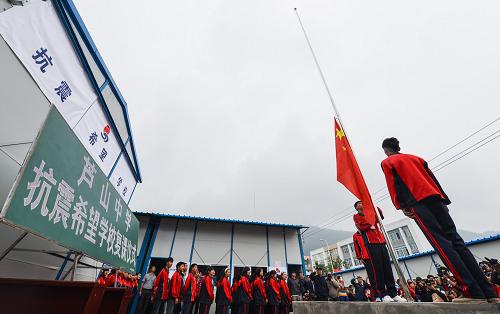 5月6日,蘆山中學(xué)師生在板房教室前舉行升旗儀式。新華社記者 白禹 攝