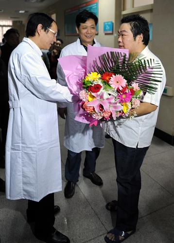 5月7日,河南大學淮河醫(yī)院醫(yī)護人員為治愈患者馬某(右一)送上鮮花祝賀。新華社記者 李博 攝