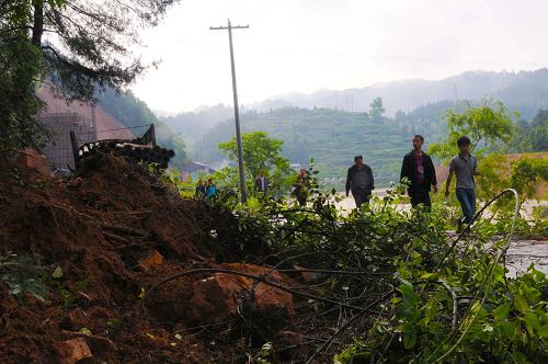 5月7日,在貴州省錦屏縣三江鎮(zhèn)銀洞村,幾名行人從因暴雨導致塌方的路段經(jīng)過。新華社發(fā)(楊秀庭 攝)